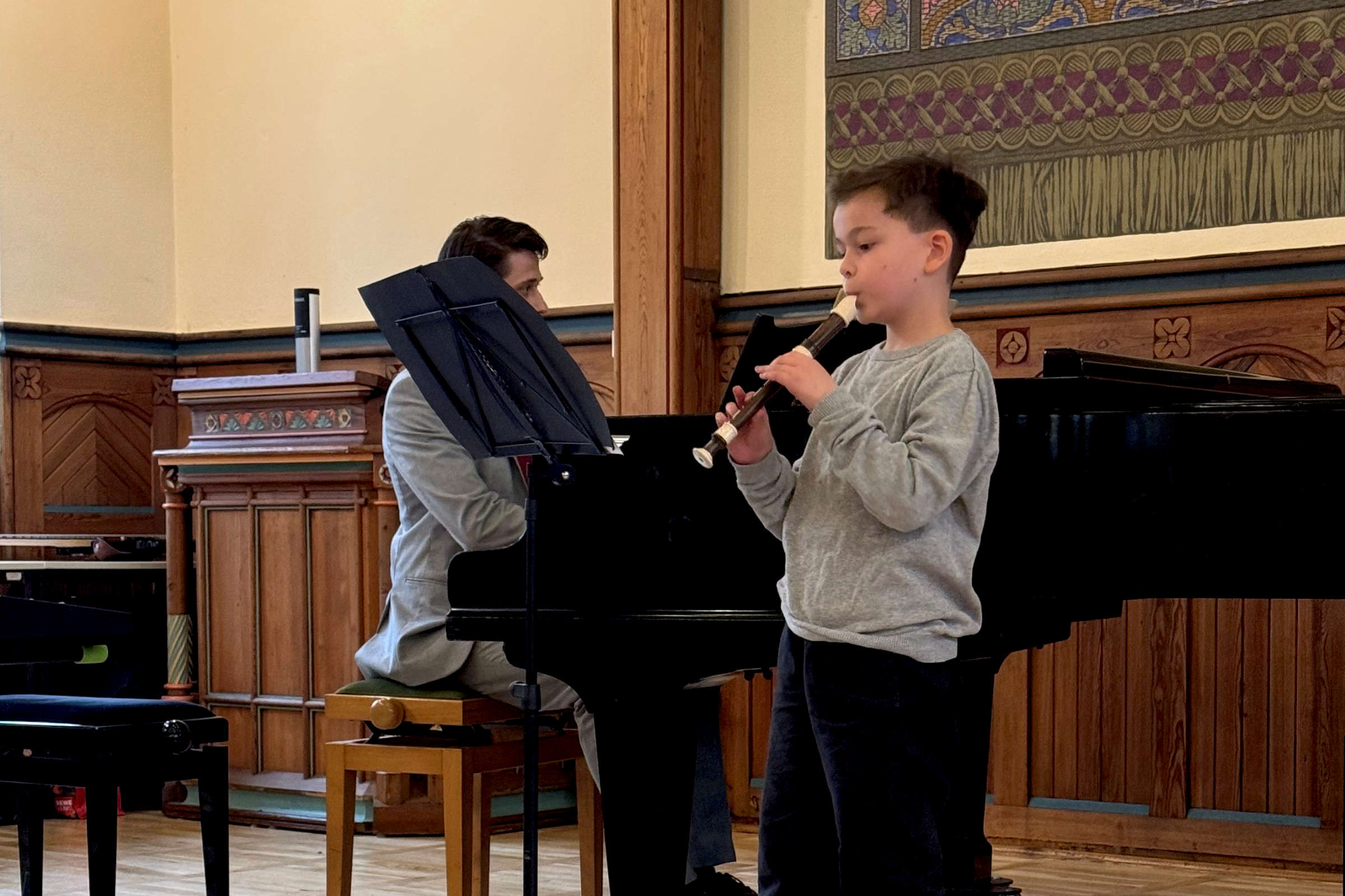 Foto: Musikschule dunkelhaariger Junge in grauem Pullover spielt Blockflöte zum Frühlingskonzert am 29.03.2025 in der Aula der Altenburger Volkshochschule