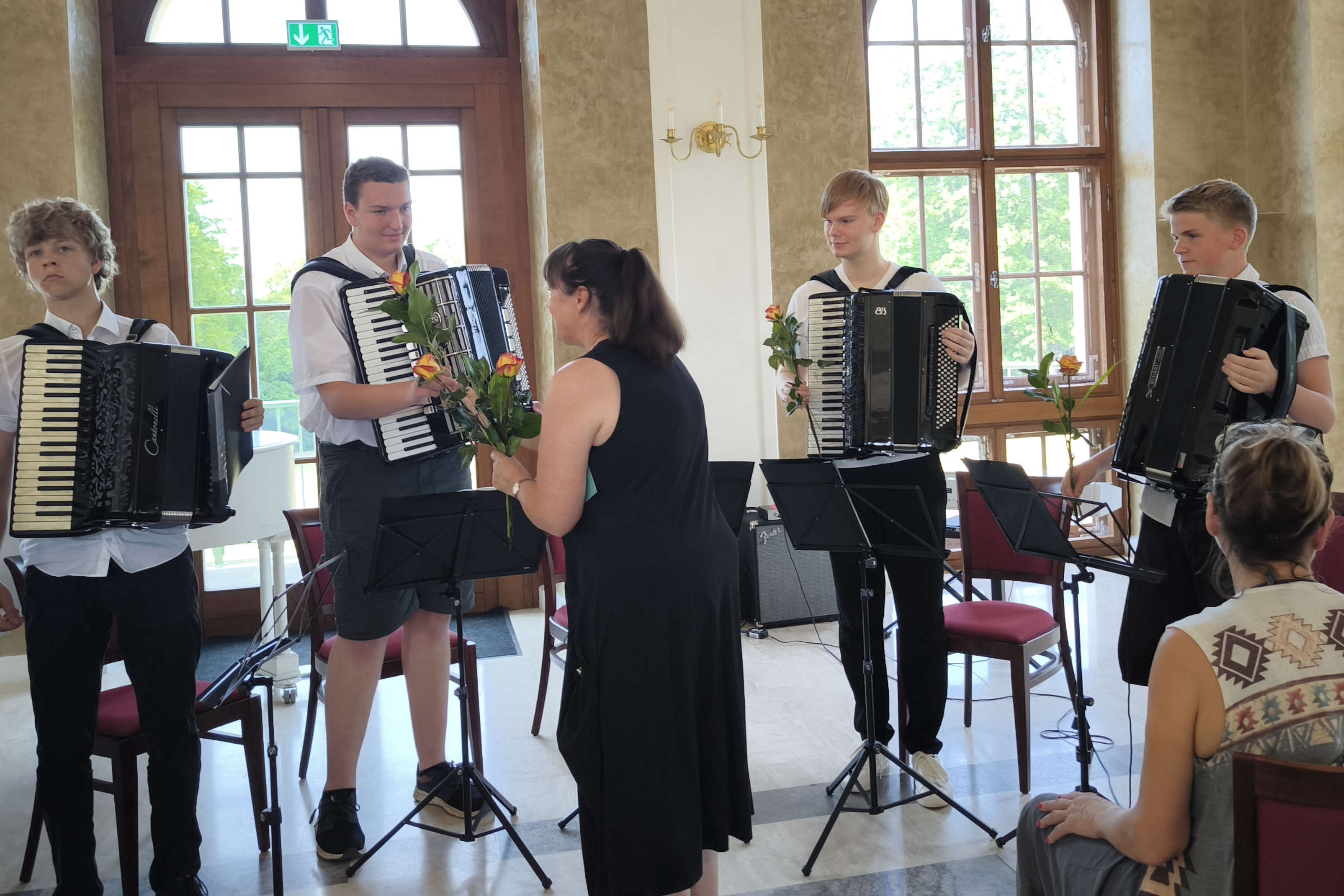 Sommerkonzert im Saal des Altenburger Teehauses am 27. Juni 2026: Blumenübergabe durch Schulleiterin Gabriele Herrmann an das Vierköpfige Akkordeonensemble