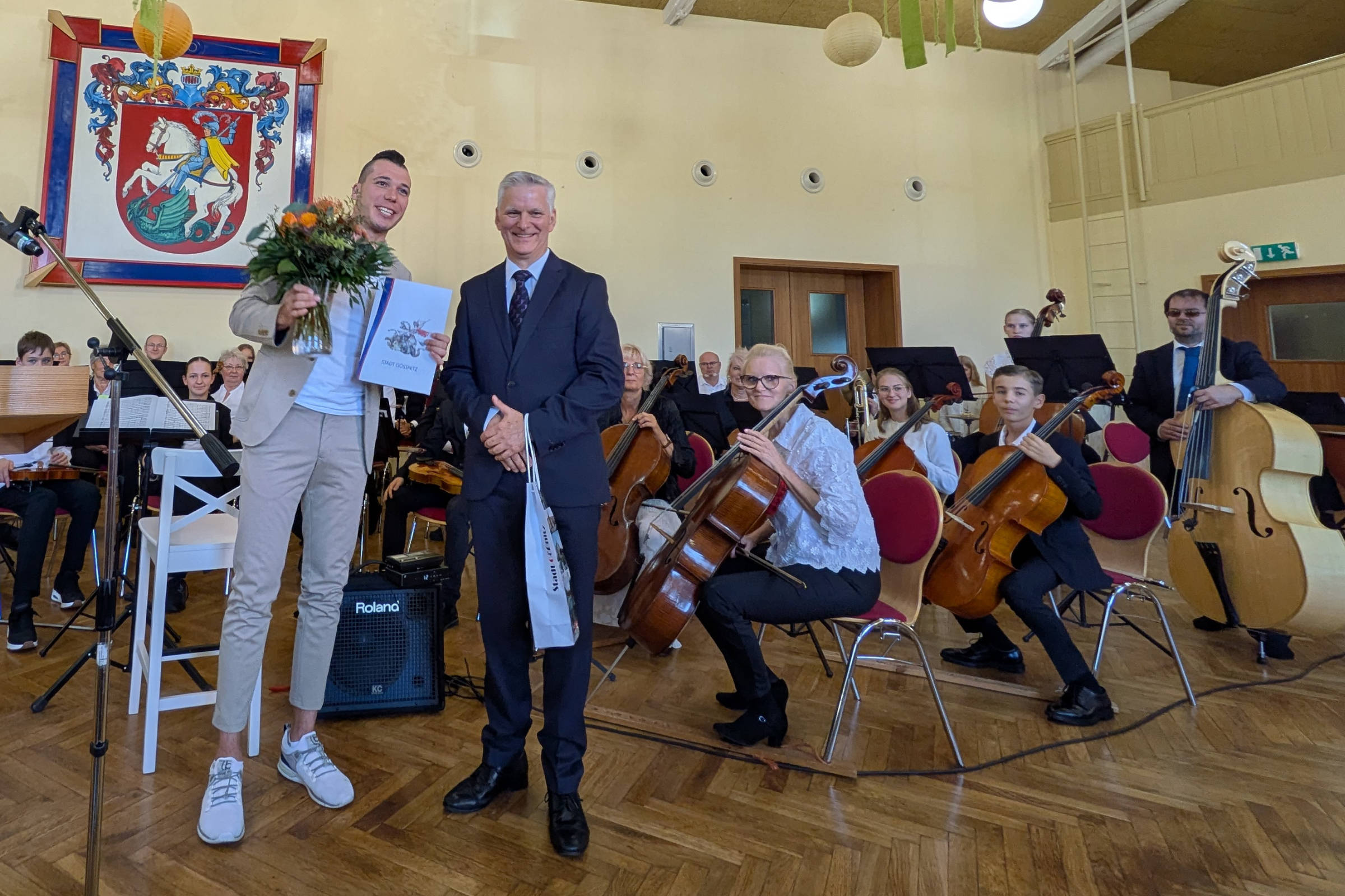 v.l.n.r.: Bürgermeister der Stadt Gößnitz Patrick Albrecht übergibt Ehrung und Blumen an bisherigen stellvertretenden Schulleiter Holger Runge anlässlich des Verabschiedungskonzertes am 26.09.2026