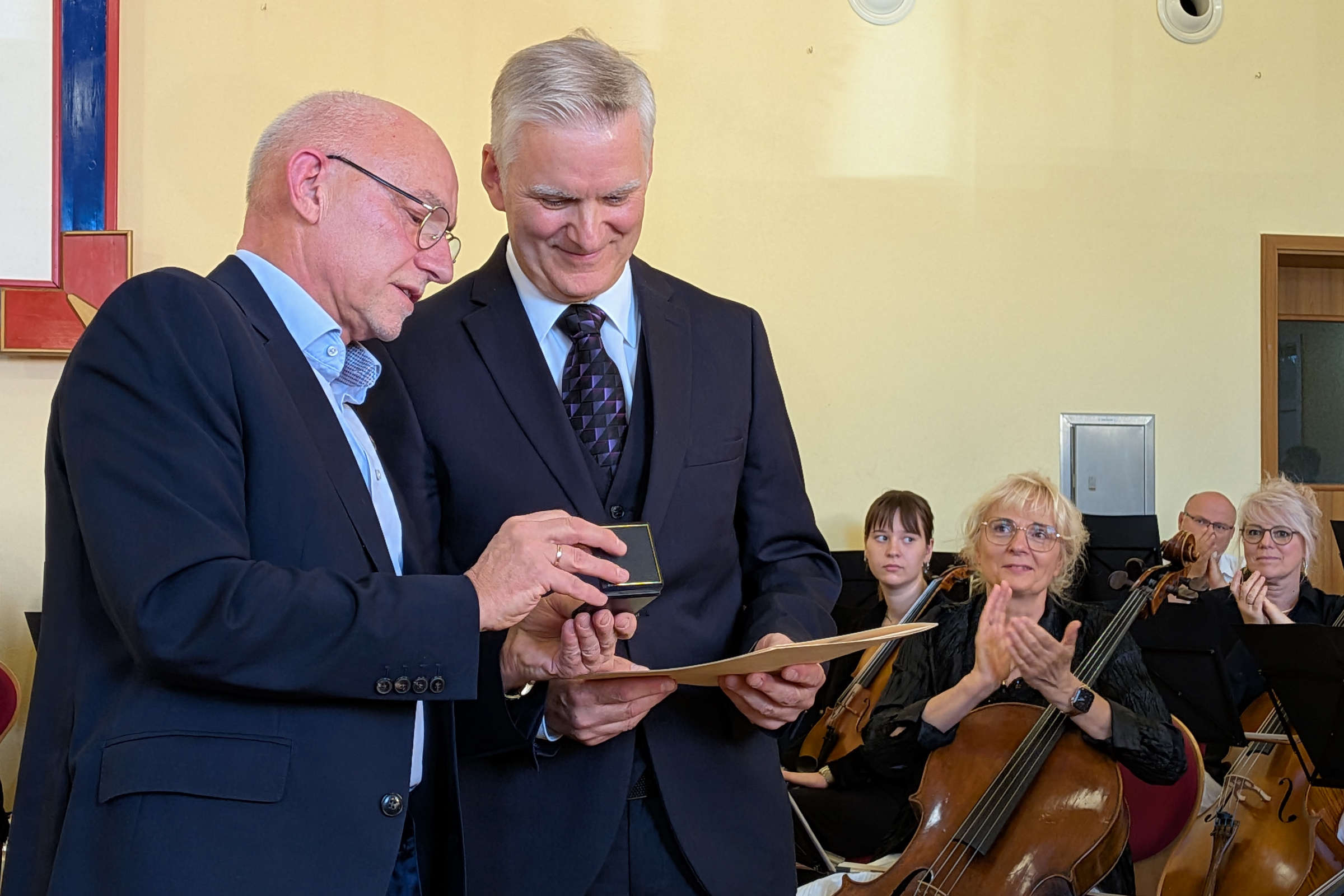 v.l.n.r.: Landrat Uwe Melzer übergibt Ehrung an bisherigen stellvertretenden Schulleiter Holger Runge anlässlich des Verabschiedungskonzertes am 26.09.2026