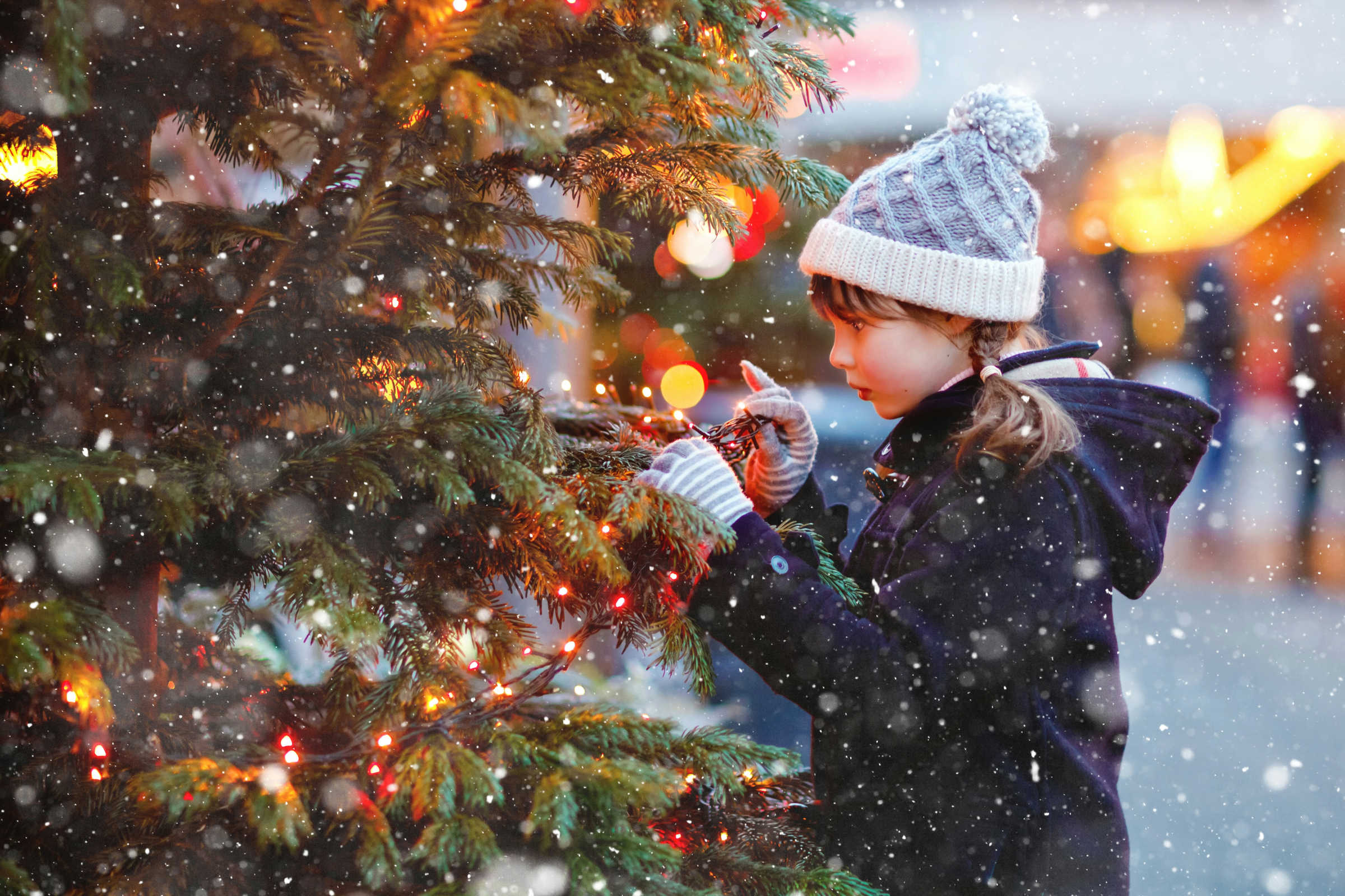 Foto: Getty Images/Unsplash.com Mädchen steht an leuchtendem Weihnachtsbaum